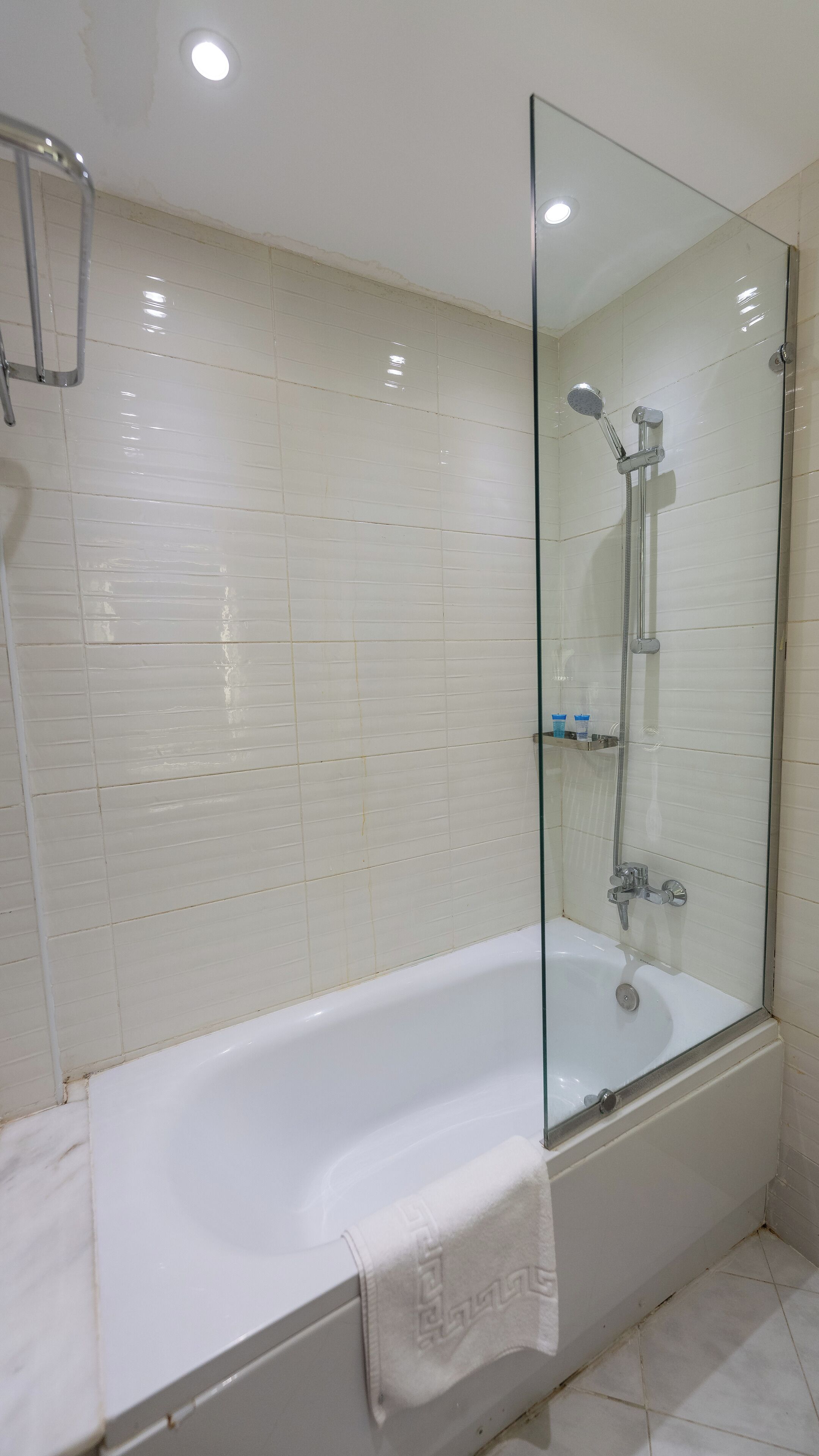 Une salle de bain moderne avec une douche à l’italienne, une baignoire blanche et des murs carrelés.