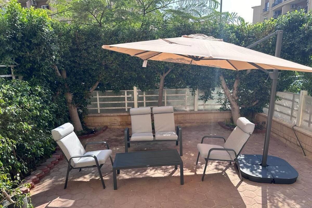 An outdoor patio with a round table, four chairs, and a large umbrella.