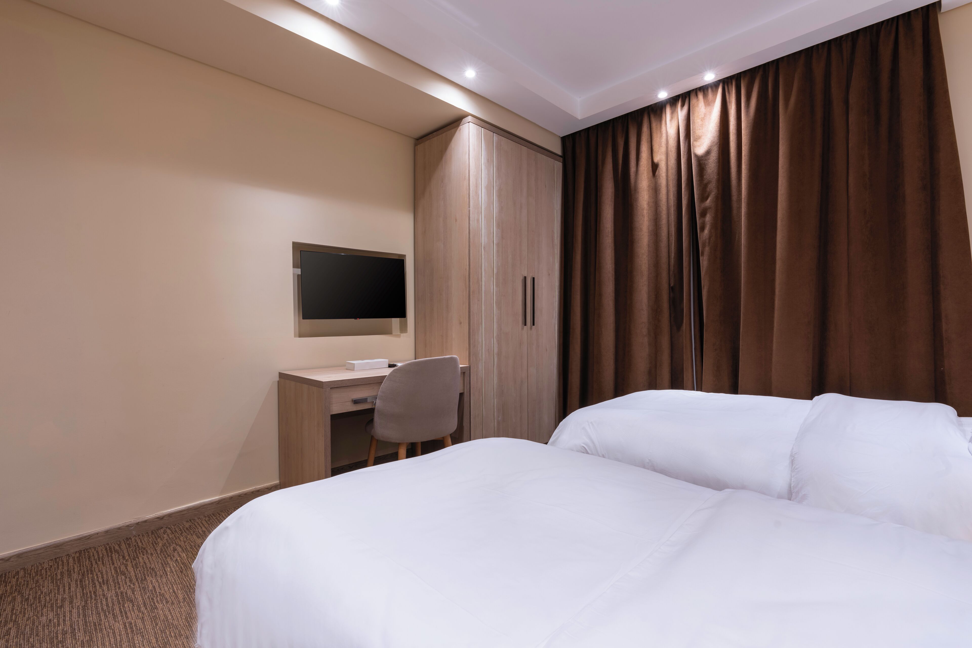 Una habitación de hotel con cama, escritorio, silla y armario.