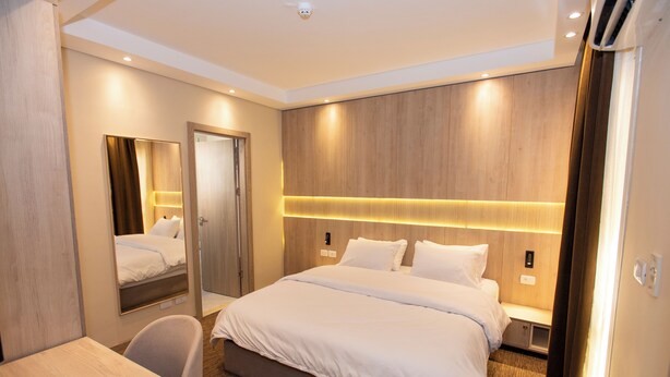Una habitación de hotel con una cama grande, un escritorio, una silla, un espejo y un armario.