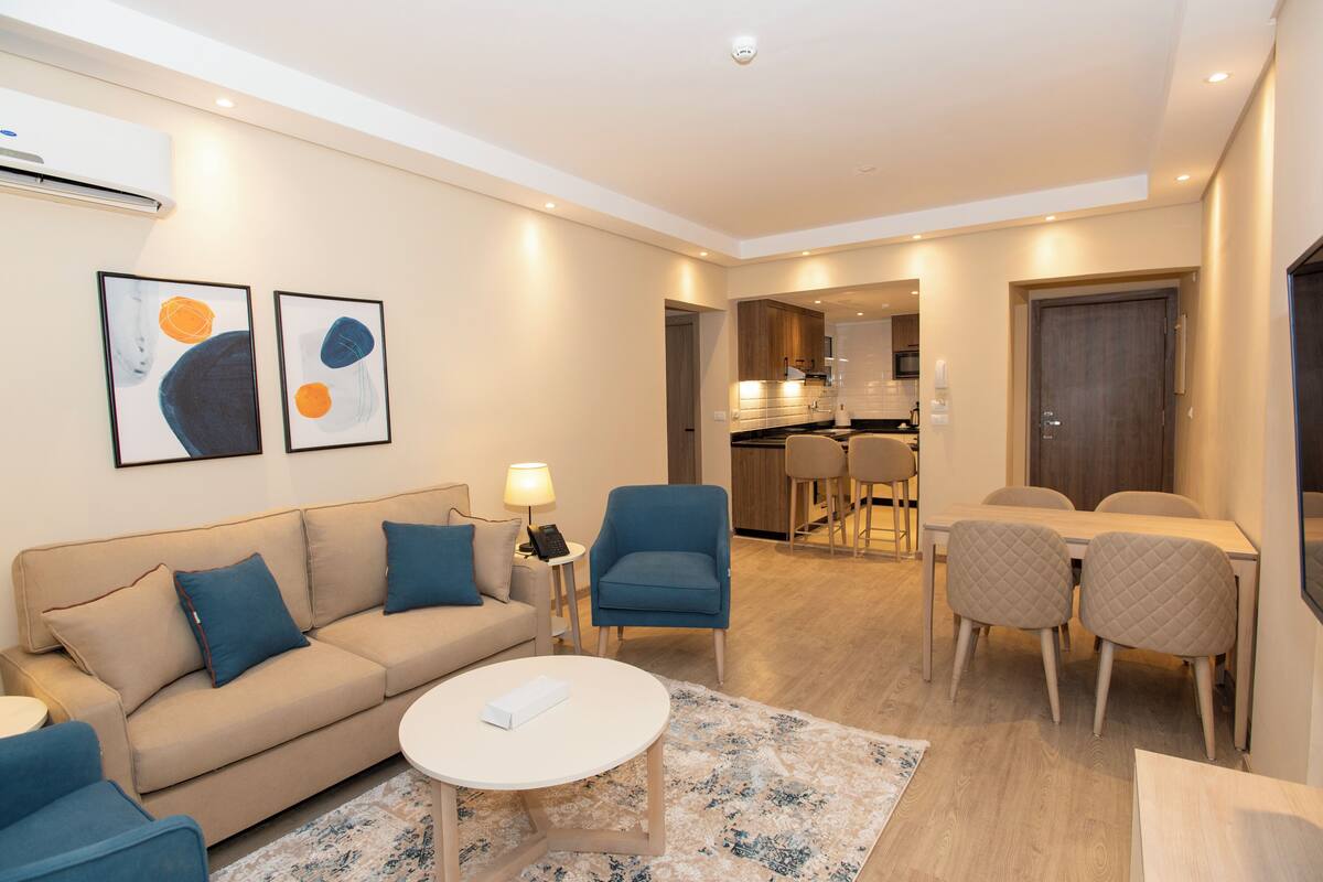 A modern living room with a sofa, armchairs, a coffee table, and artwork on the wall.