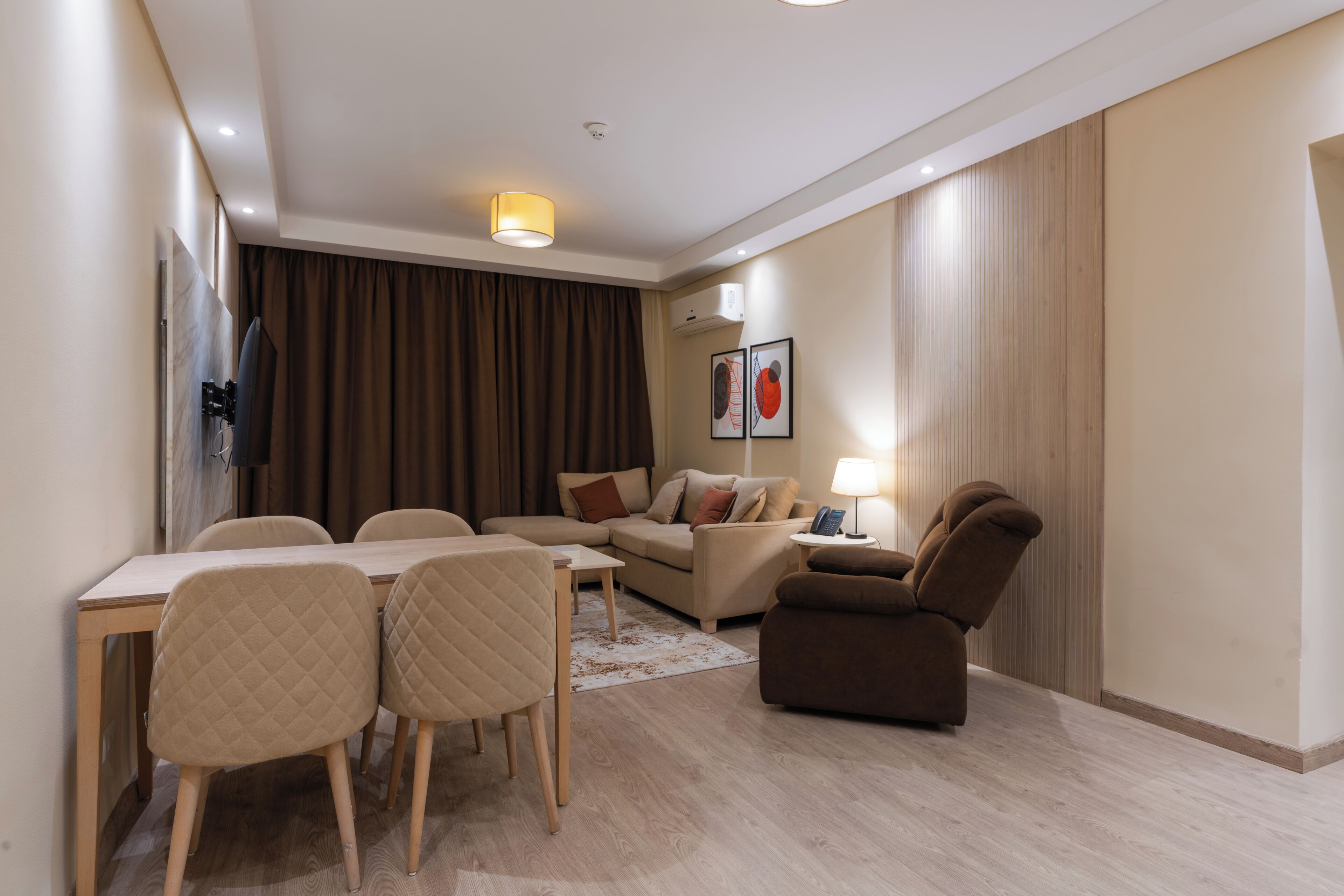 A modern hotel room with a dining area, a sofa, and a recliner.