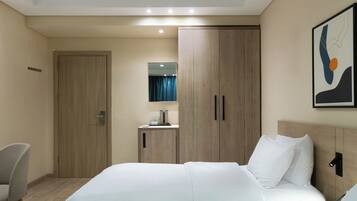A hotel room with a bed, a desk, a wardrobe, and a mirror.