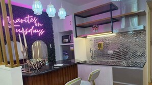A modern kitchen with a neon sign, pendant lights, and a bar area with stools. - Vacation Retreat in the city (Parañaque)