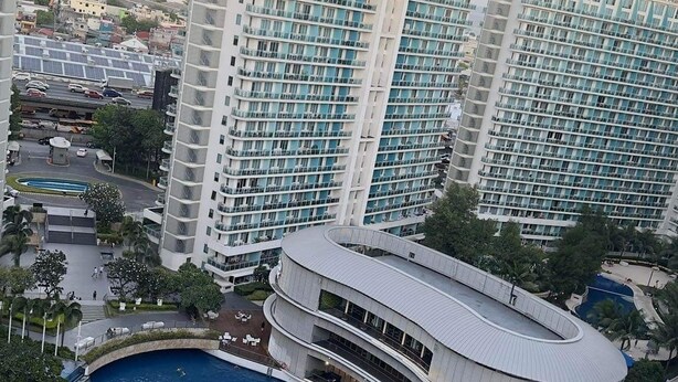 A modern hotel with a large central pool, multiple balconies, and a view of surrounding buildings. - Vacation Retreat in the city (Parañaque)
