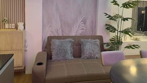 A modern living room with a brown sofa, a large chandelier, a wooden cabinet, and a plant. - Vacation Retreat in the city (Parañaque)