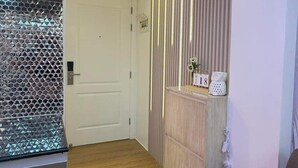 A modern interior with a wooden floor, a sofa, a cabinet with a vase, and a decorative wall with vertical lines. - Vacation Retreat in the city (Parañaque)