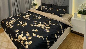 A modern bedroom with a large bed, a chandelier, and a wall-mounted light fixture. - Vacation Retreat in the city (Parañaque)