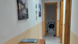 A hallway with a wooden desk, a wall-mounted fan, and a door leading to a laundry room. - Intero appartamento 70mq  (Scalea)