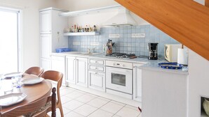 Una cocina con gabinetes blancos, una estufa y una cafetera.