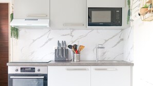 A kitchen with white cabinets, a built-in oven, a microwave, and a stainless steel sink.