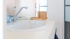 A modern bathroom with a white sink, a chrome faucet, and a wooden soap dish.