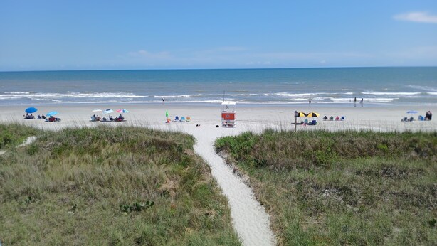 A beach with a sandy path leading to the water, beach chairs, umbrellas, and a lifeguard tower. -  Cherry Grove Beach Oceanfront 
Finestere -F1 (North Myrtle Beach)