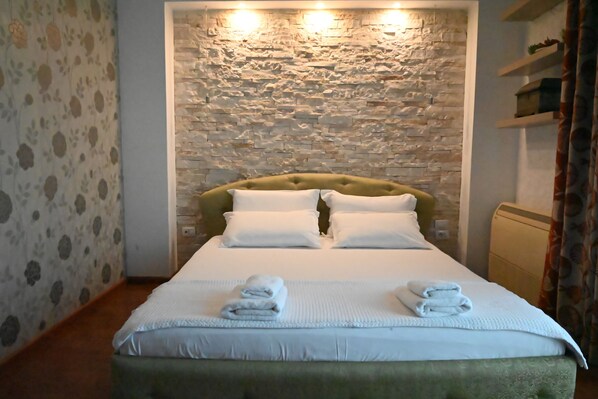 A neatly made bed with white linens and two folded towels on the bed.