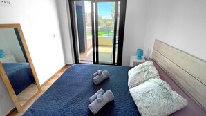 Une chambre avec un grand lit, un miroir, une table de chevet et une vue sur une piscine, accessible par une porte coulissante.