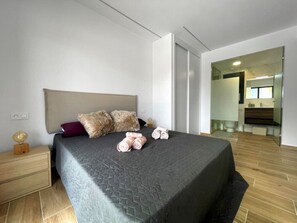 A modern bedroom with a large bed, a nightstand, and a mirror. - Apartment Villamartin Valentinogolf III (Orihuela Costa)