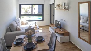 Un salon moderne comprenant un coin repas, un canapé, un téléviseur et un grand miroir.