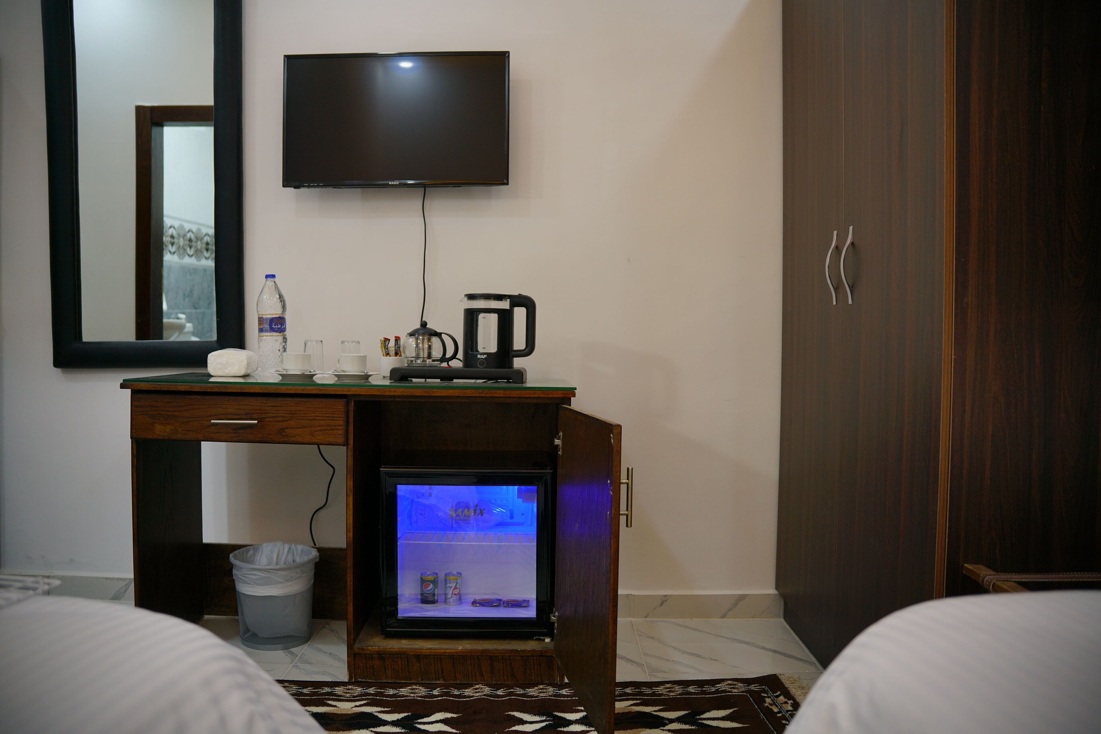 Ett hotellrum med en säng, ett skrivbord med en kaffebryggare, en tv och en minibar.
