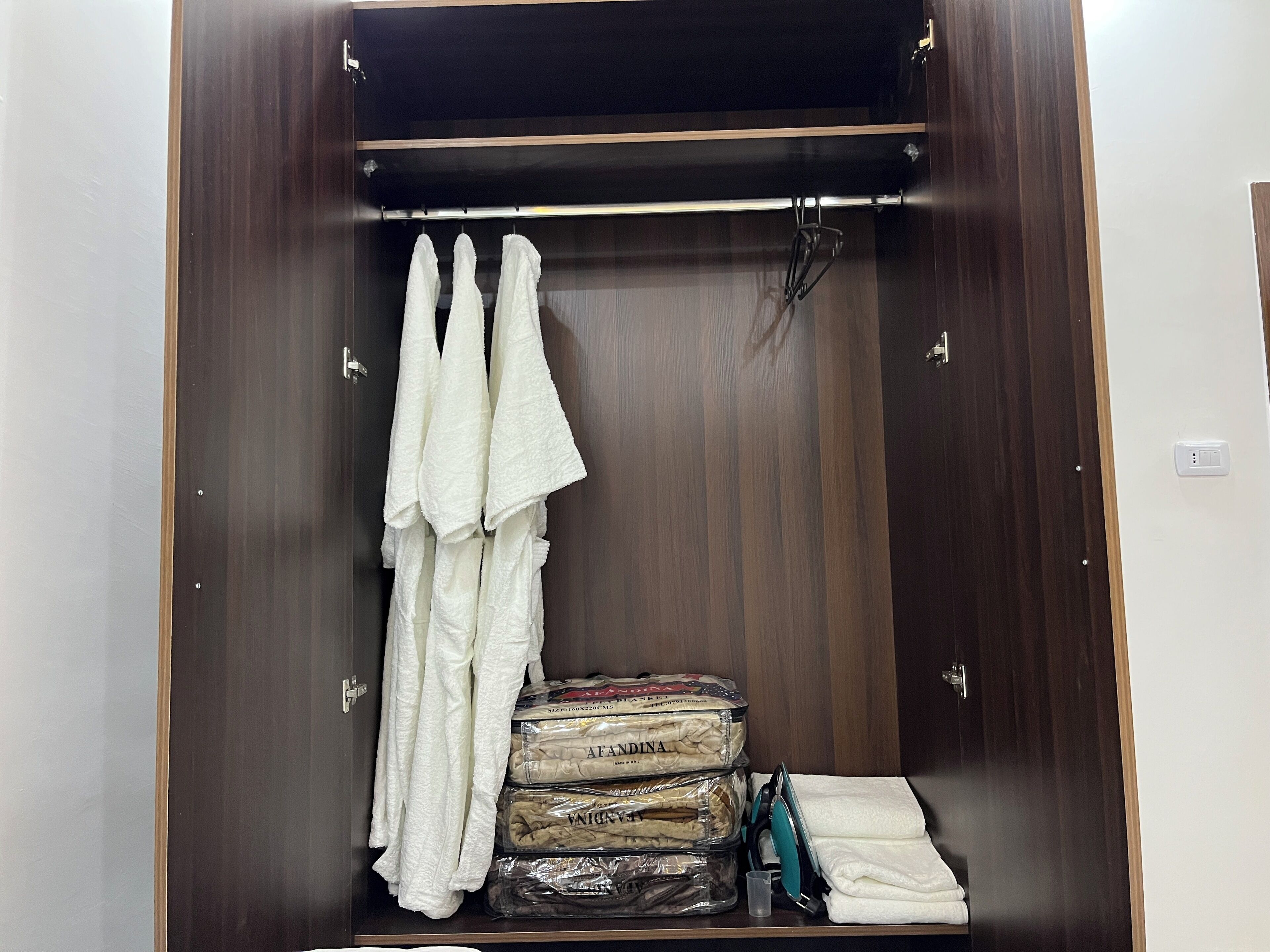 A walk-in closet with hanging towels, neatly stacked linens, and a pair of scissors.