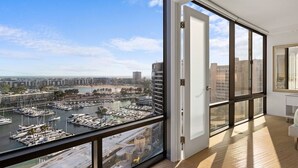 Un appartement moderne doté d’un grand balcon offrant une vue sur un port de plaisance et sur le paysage urbain.