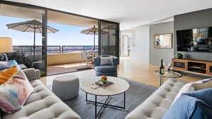 A modern living room with a sofa, coffee table, and a balcony with umbrellas. - Gorgeous Luxury Highrise w/Spectacular Marina & Ocean Views (Marina Del Rey)