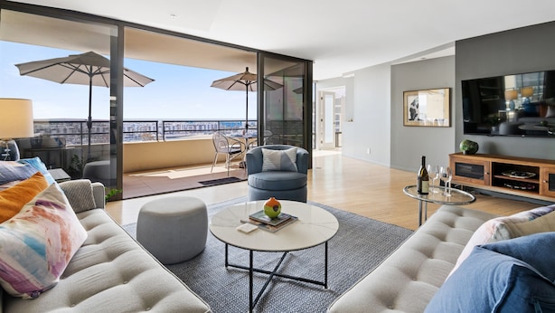 Un salon moderne avec un canapé, une table basse et un balcon agrémenté de parasols.