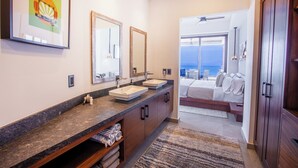 Une salle de bain moderne avec un comptoir en granit, deux lavabos et un grand miroir.