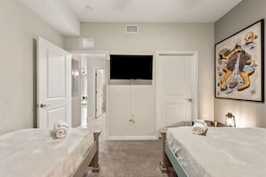 A hotel room with two beds, a flat-screen TV mounted on the wall, and a painting on the wall.