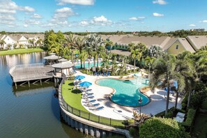 A resort with a large pool, lounge chairs, and a dock extending into a body of water. - 15103 Resort 2BR Condo Apt by Disney World Orlando (Kissimmee)