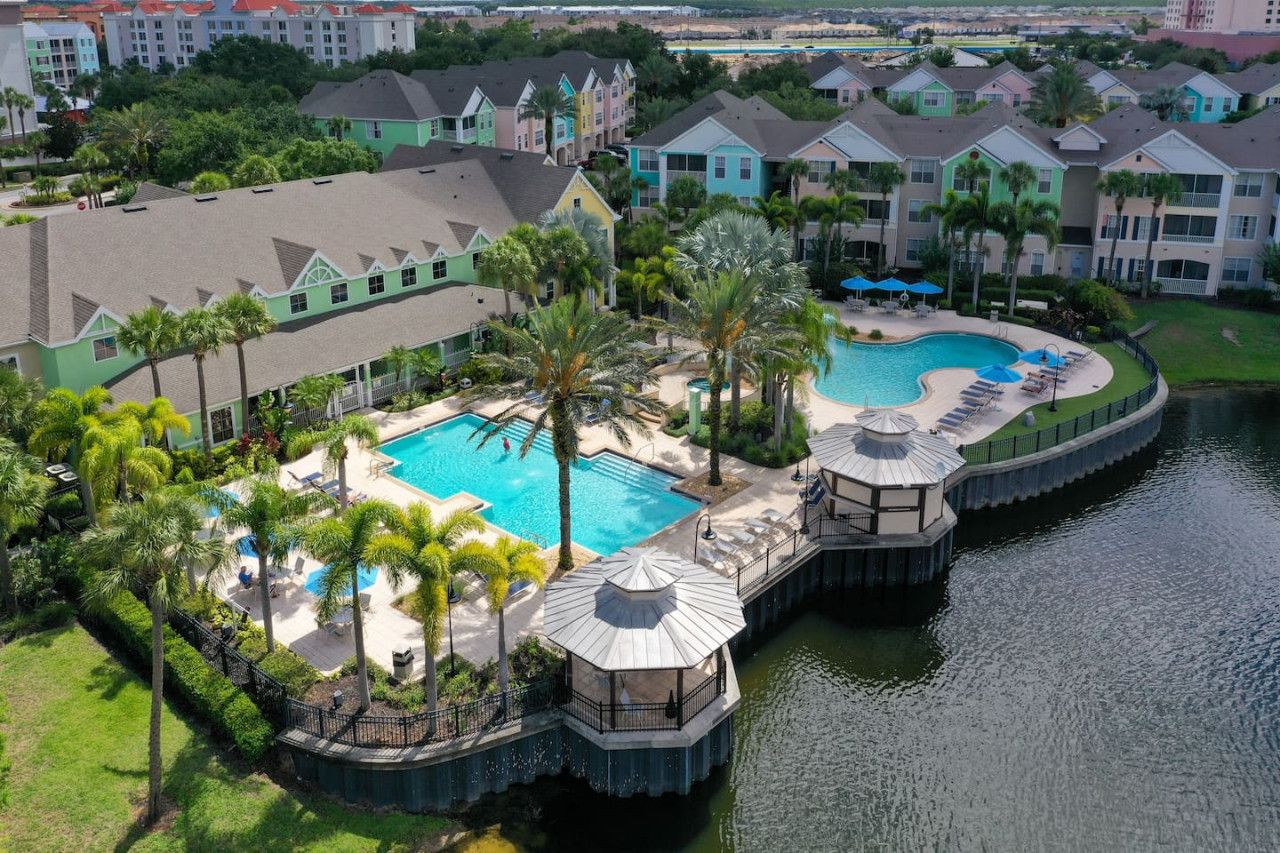 A resort with a central swimming pool surrounded by palm trees and a water feature.