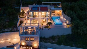 A modern villa with a rooftop pool, multiple balconies, and a stone facade. - Casa GENI with a heated pool, 3 bedrooms, an organic garden, sea views (Borak)