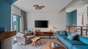 A modern living room with a large flat-screen TV, a wooden coffee table, a blue sofa, and a brown armchair. - Casa GENI with a heated pool, 3 bedrooms, an organic garden, sea views (Borak)