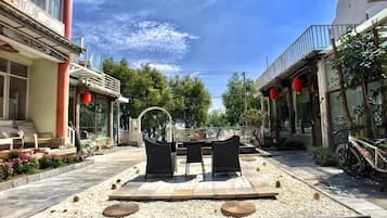 An outdoor seating area with a table and chairs, surrounded by a gravel path and greenery.