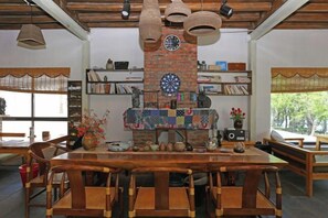 Een eetgedeelte met een metselwerk open haard, houten meubels en planken met boeken en decoratieve objecten.