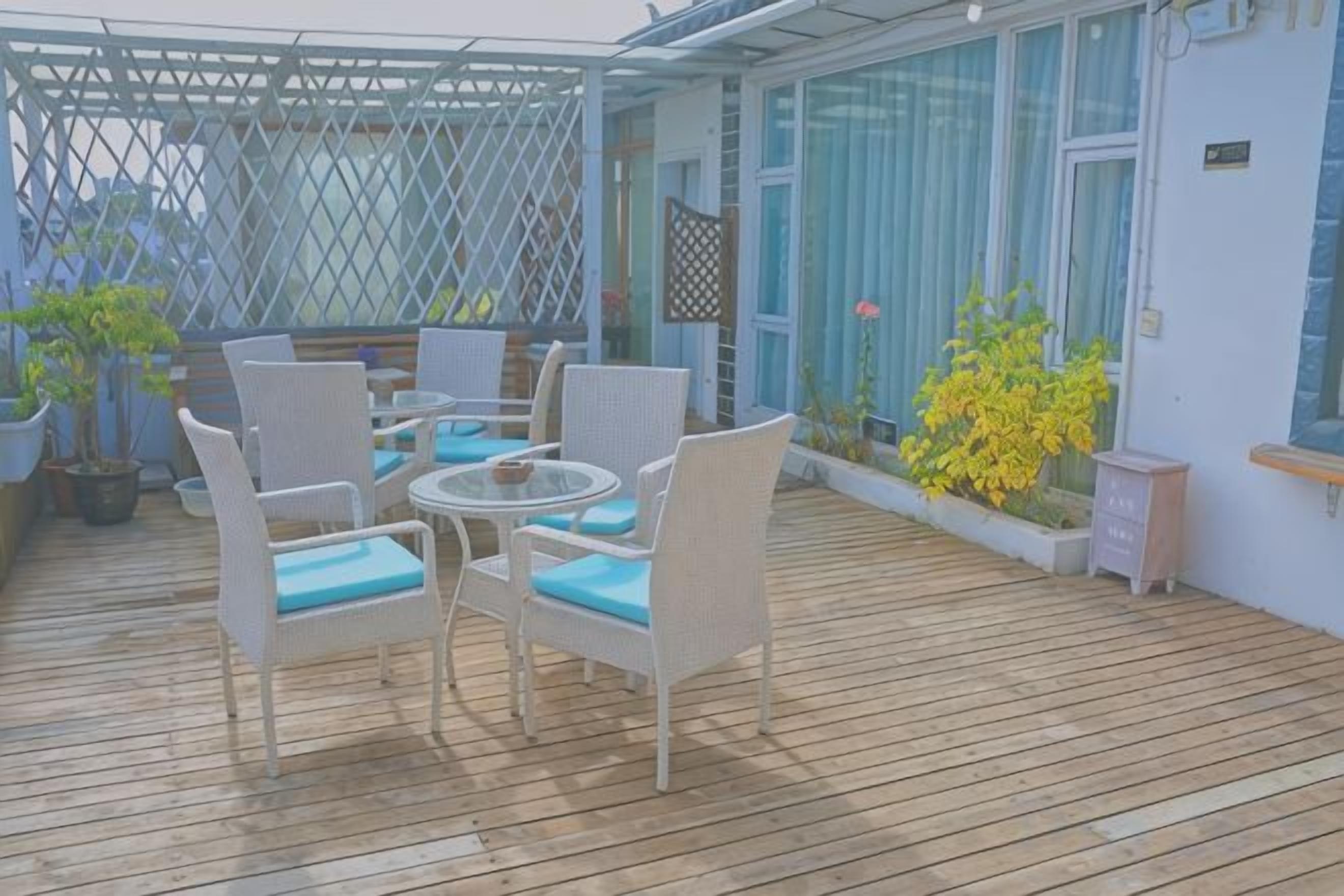 An outdoor patio with wicker furniture and potted plants.