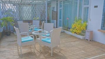 An outdoor patio with wicker furniture and potted plants.