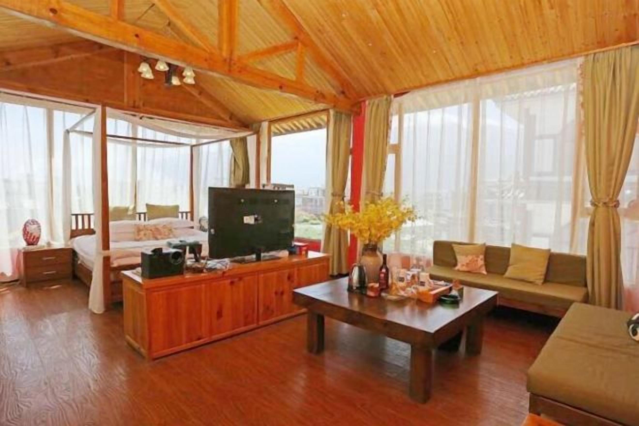 A spacious living room with a wooden ceiling, a sofa set, a coffee table, and a TV.
