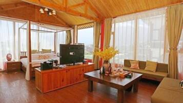 A spacious living room with a wooden ceiling, a sofa set, a coffee table, and a TV.