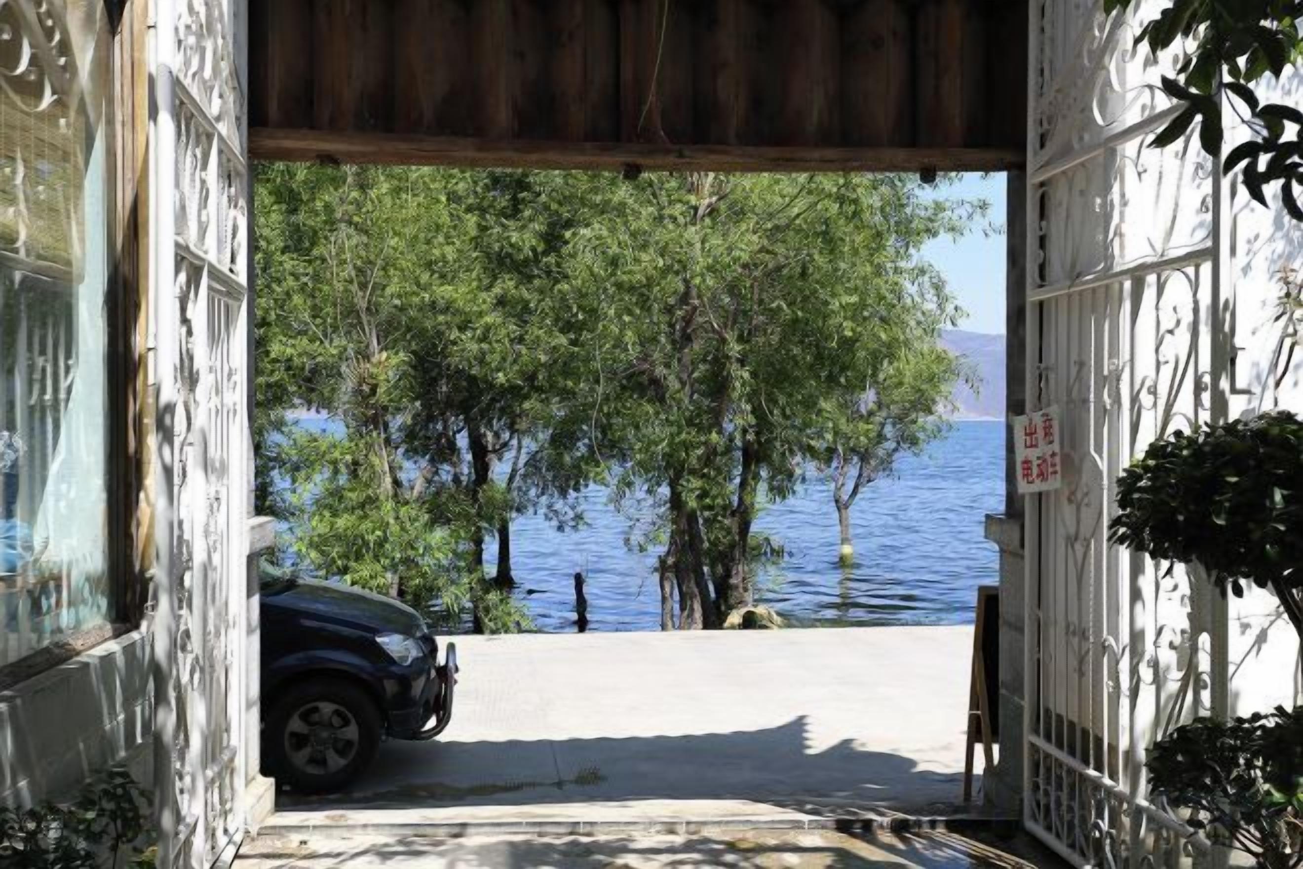 A doorway leading to a view of a lake with trees and a parked car.