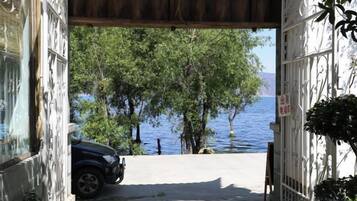 A doorway leading to a view of a lake with trees and a parked car.