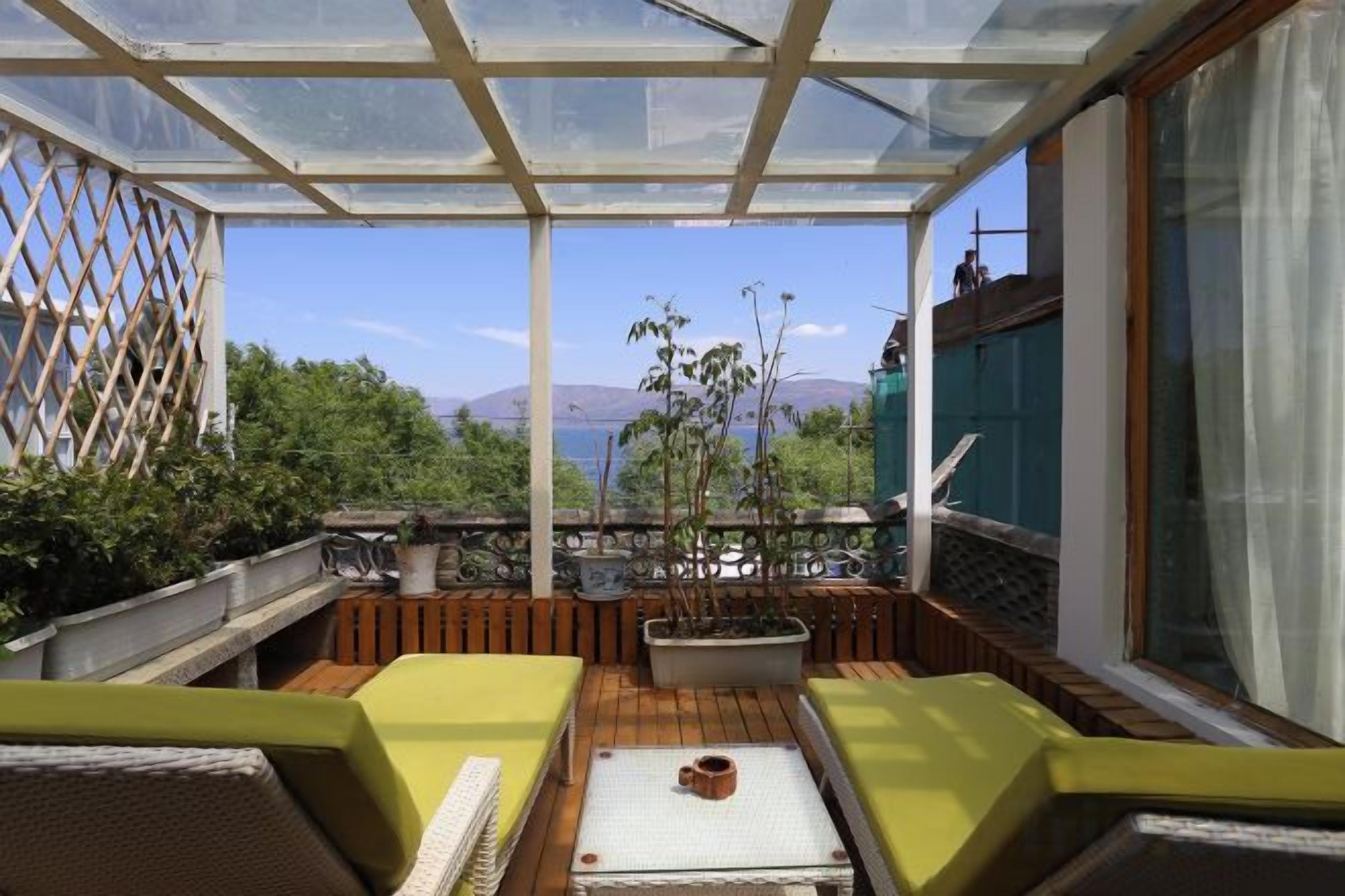 Un espacio de estar al aire libre cubierto con suelo de madera, sillas acolchadas y una mesa.