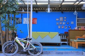 A room with a blue wall, a bicycle, a table, and a bench. - Haiyang Lanlan Erhai Garden Sea View Inn (Dali City)