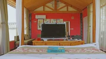 A bedroom with a bed, a television, and a desk with a computer.