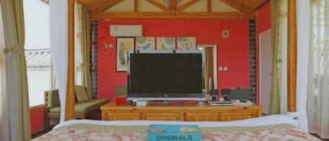 A bedroom with a bed, a television, and a desk with a computer.