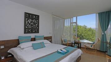 A hotel room with a large bed, a desk, and a view of the outdoors.