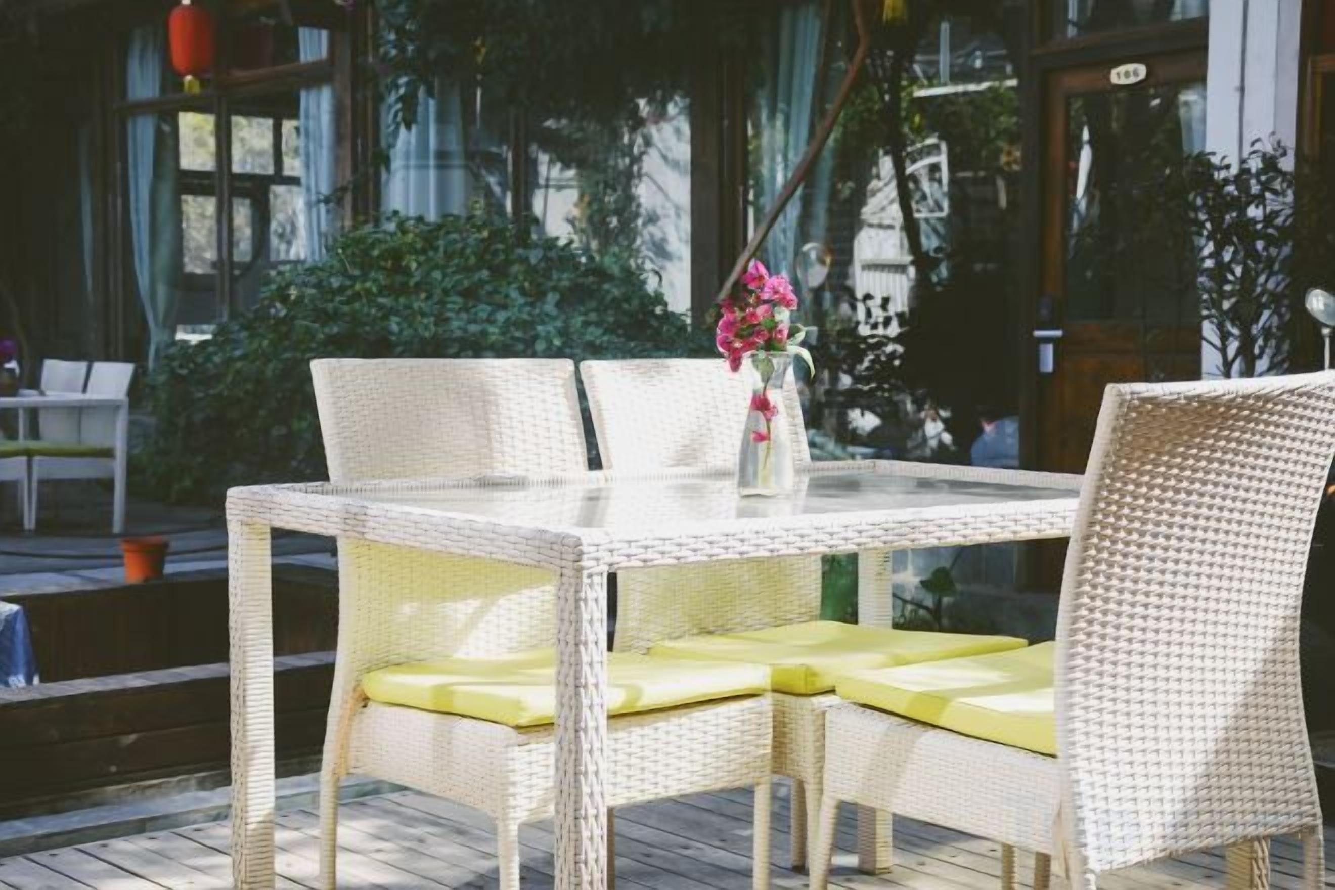 A wicker table with yellow cushions and a vase with flowers.