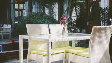 A wicker table with yellow cushions and a vase with flowers.