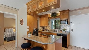 A compact kitchen with wooden cabinets, a granite countertop, and a dishwasher. - Pacific Shores A302 3 Bedroom Condo (Kihei)