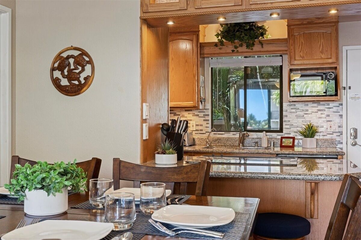 Une cuisine moderne avec des meubles en bois, un four encastré et une grande fenêtre.