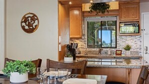 A modern kitchen with wooden cabinets, a built-in oven, and a large window. - Pacific Shores A302 3 Bedroom Condo (Kihei)